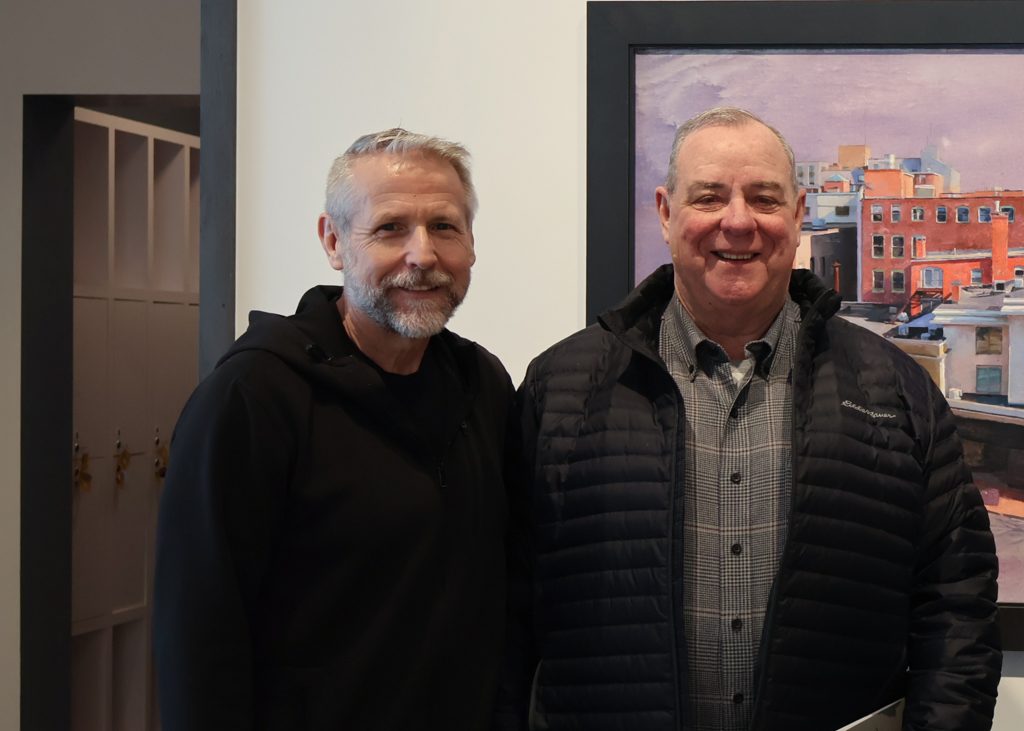 Museum Director, Bob Burns, and the Honorable Neil O'Leary  pose for a photograph in front of the Peter Poskas painting of Waterbury at Mattatuck Museum. 