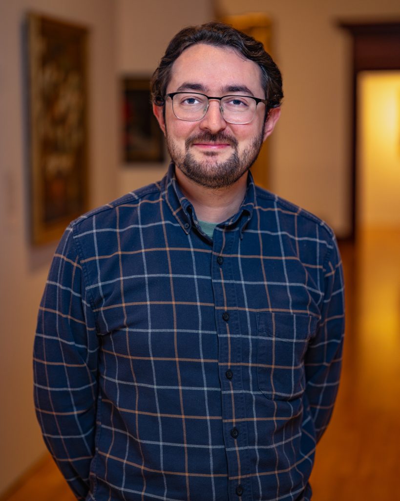 Caleb Weissman in blue striped shirt wearing glasses