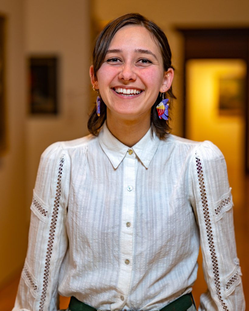 Lillian Hayward in a white blouse with colorful earrings