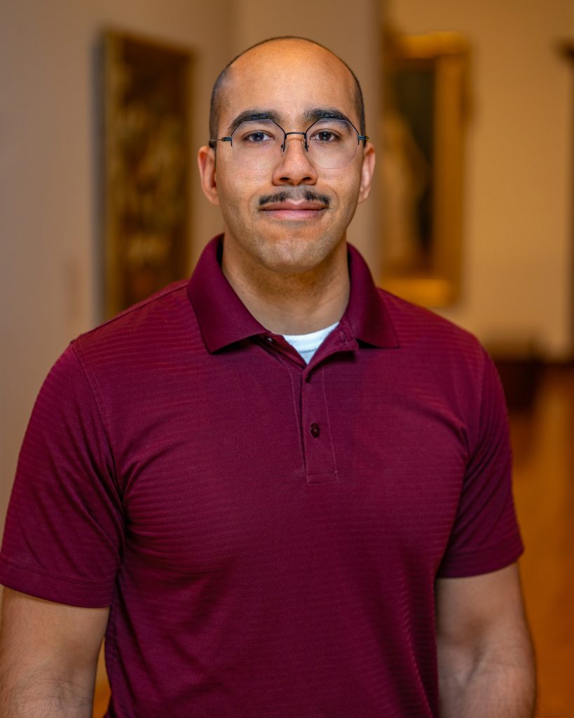 Quinn Fabas-Smith in glasses and a dark red shirt