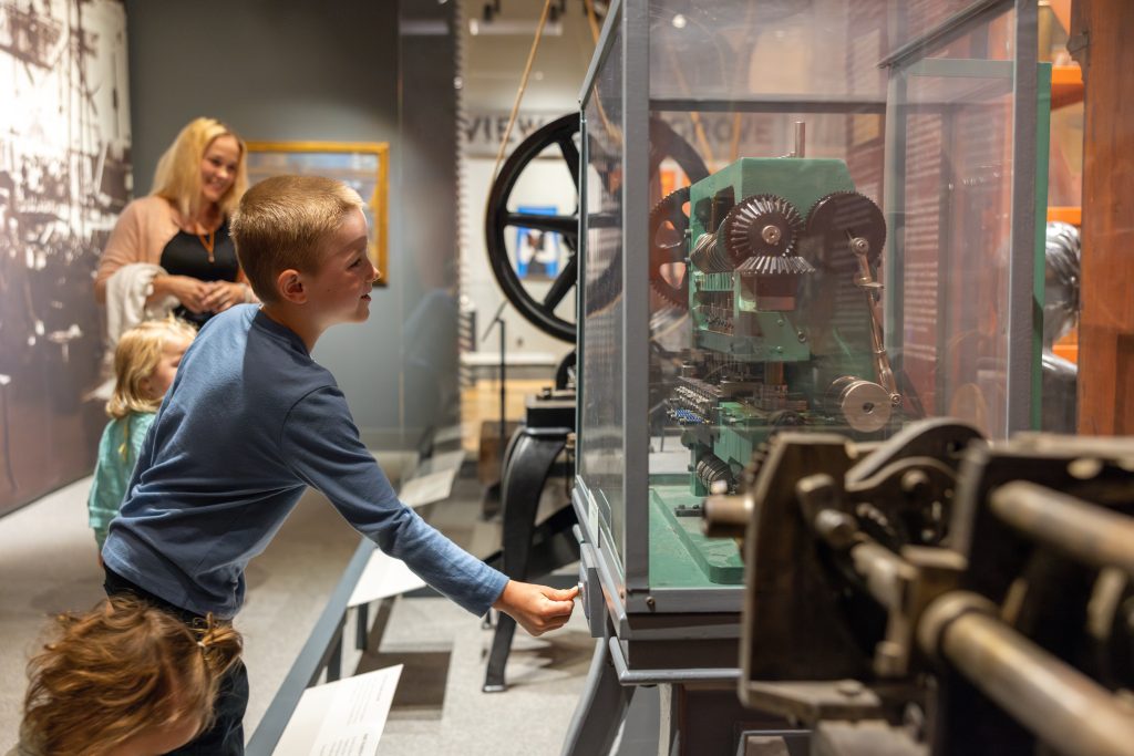 boy pushing button on the machinery in history gallery