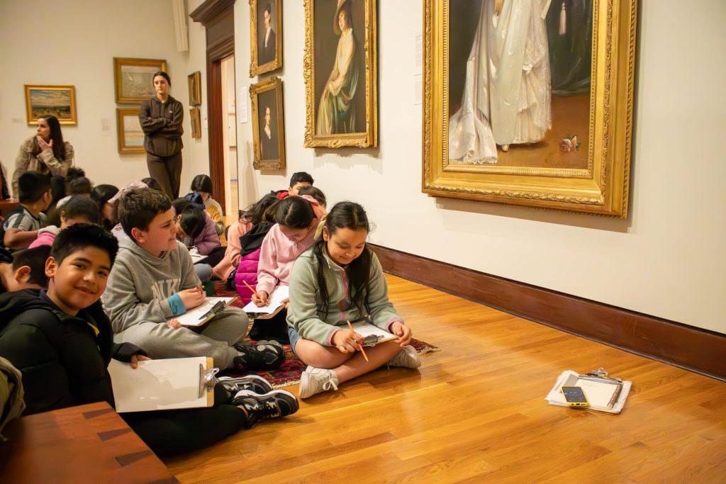 Group of kids on a school tour sketching in the gallery