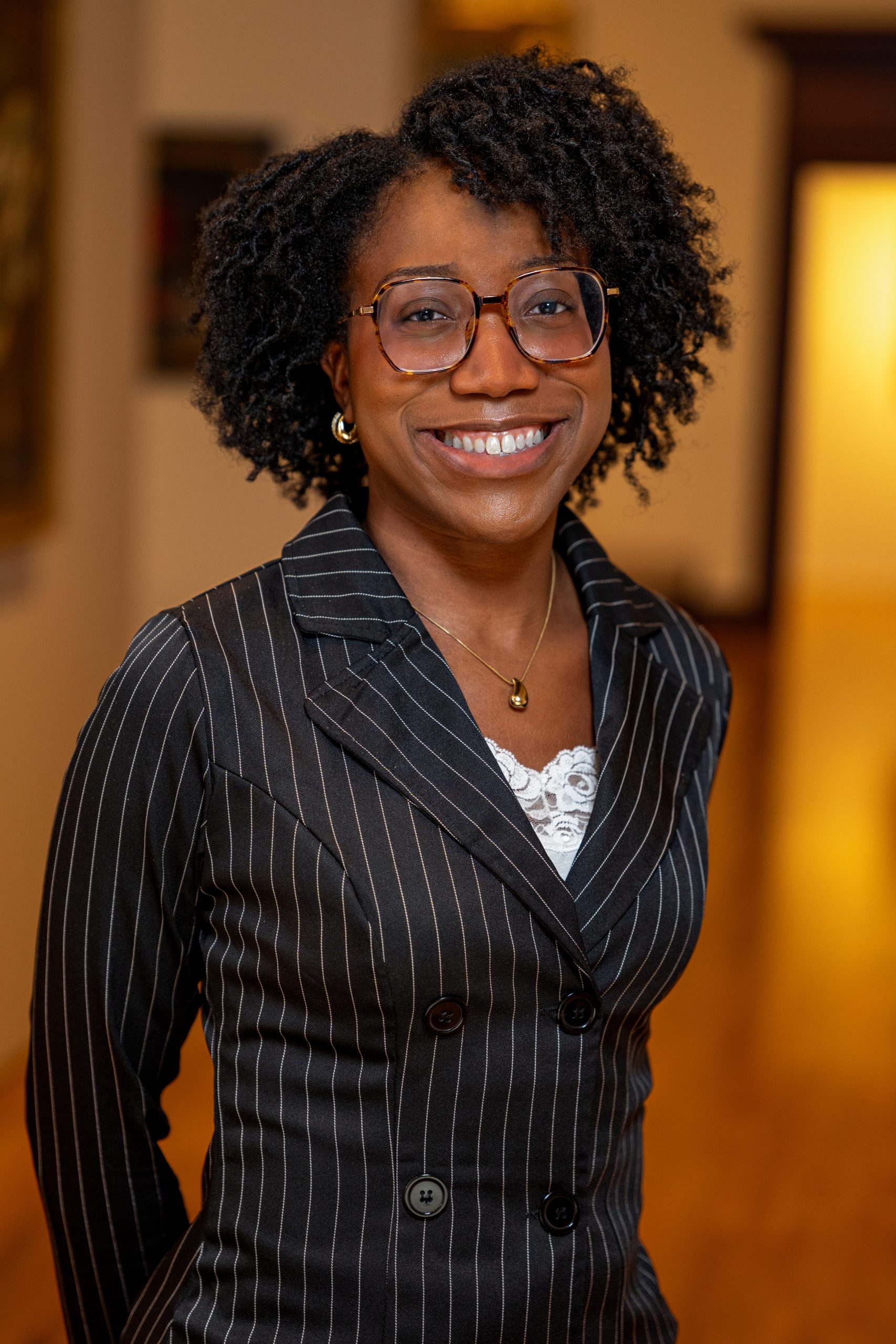 Julie Francois headshot in striped suit with glasses